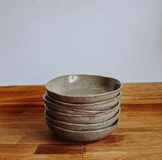 a stack of ceramic bowls sitting on top of a wooden table