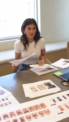 a woman sitting at a table with papers and laptop