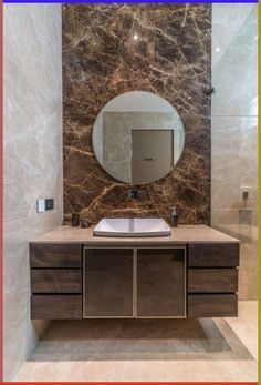 a bathroom with marble walls and a round mirror on the wall above the vanity area