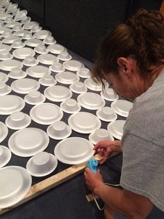 a woman is painting white plates on the floor