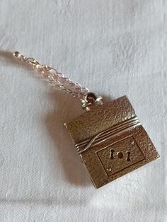 a gold necklace with a small metal box on it