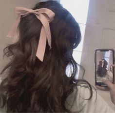 a woman is taking a selfie in the mirror with her hair tied up and wearing a pink bow