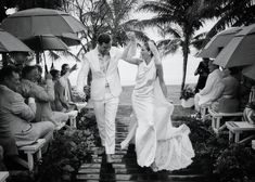 a bride and groom walk down the aisle under umbrellas