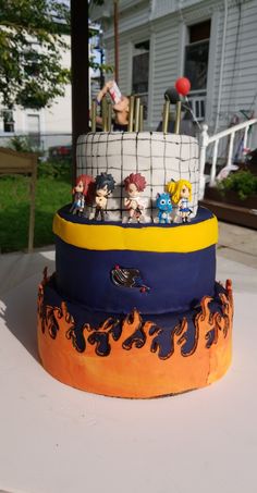 a three tiered cake with cartoon figures on it's sides and flames around the edges