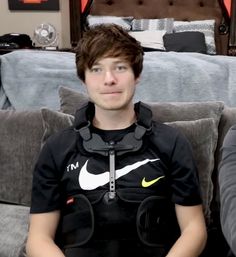 a young man sitting on top of a gray couch