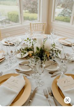 the table is set with white and gold place settings