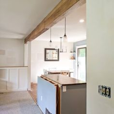 an open kitchen and living room area in a house with wood beams on the ceiling