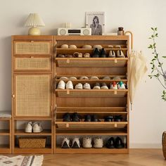 a wooden shoe rack filled with pairs of shoes next to a lamp and rug on the floor