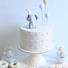 an elephant cake and cupcakes on a table