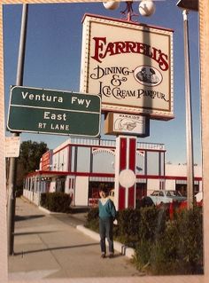 a woman standing in front of a restaurant next to a sign for the famous dining and ice cream parlor