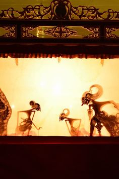 three statues in front of a window with light coming through the glass and shadows on the wall