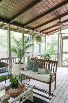 a porch with couches, tables and potted plants on the back deck area