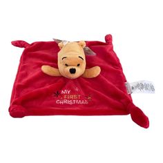 a winnie the pooh plush toy laying on top of a red blanket with merry lettering