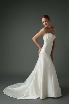 a woman in a white wedding dress posing for the camera with her hands on her hips