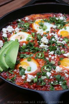 an egg dish in a skillet topped with cheese and avocado