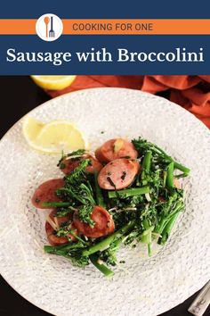 sausage and broccoli on a white plate with lemon wedges in the background