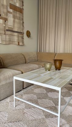 a living room with a couch, coffee table and vases on the carpeted floor