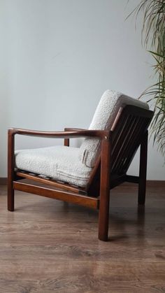 a chair sitting on top of a hard wood floor next to a potted plant