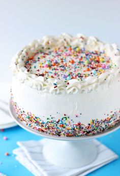 a cake with white frosting and sprinkles sitting on top of a table