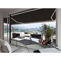 a living room with a glass table and white chairs next to a large window overlooking the city