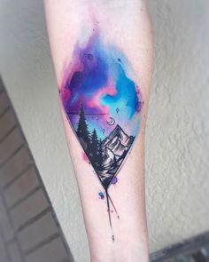 a watercolor tattoo with mountains and trees on the arm