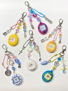 many different key chains are arranged together on a white surface with beads and charms attached to them