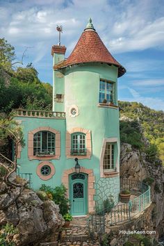 a blue and pink house on top of a hill