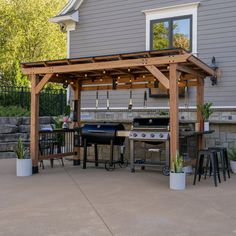 an outdoor kitchen and grill area with potted plants