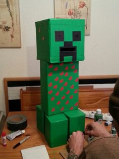 a man is making a minecraft creeper figure out of paper mache blocks