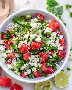 a white bowl filled with watermelon, cucumber and feta cheese