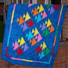 a colorful quilt hanging from the side of a brick building