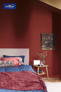 a bedroom with red walls and blue bedding