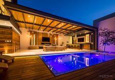 an indoor swimming pool in the middle of a wooden deck and patio area at night