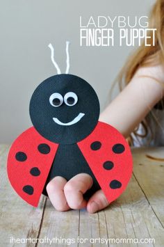 a ladybug finger puppet is held up by a child