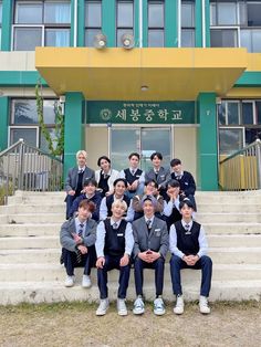 a group of young men sitting on top of steps in front of a school building