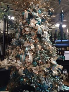 a decorated christmas tree with blue and white ribbons on it in a store ornament shop