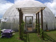 a large white greenhouse with lots of green plants growing around it and an open door