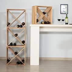 a white table with some wine bottles and glasses on it next to a wooden shelf