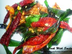 colorful vegetables are piled on top of each other in a white plate with green and red leaves