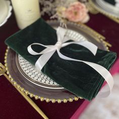 a green napkin with a white bow on it sitting on top of a silver plate