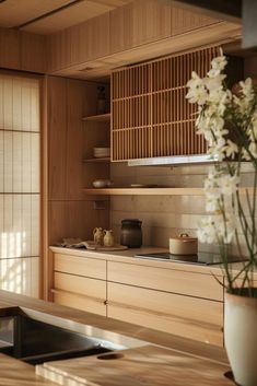 a vase filled with white flowers sitting on top of a wooden counter next to a window