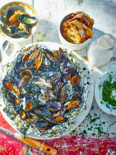 an overhead view of mussels on a plate with other dishes in the background