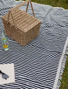 a picnic blanket on the grass with a basket and sunglasses