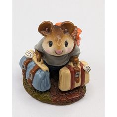 a figurine of a mouse sitting on top of a trunk holding a suitcase