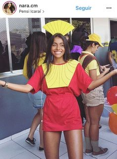 a woman in a red and yellow dress with her arms out while standing next to other people