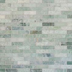 a white toilet sitting next to a green tiled wall