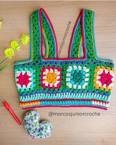 a crocheted purse next to flowers and a pair of scissors on a table