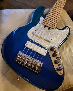 a blue electric guitar sitting on top of a bed