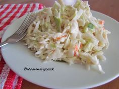 a white plate topped with coleslaw next to a fork