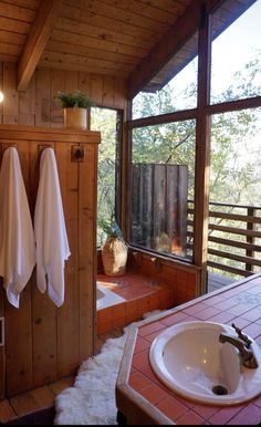 a bathroom with two white towels hanging on the wall next to a sink and window